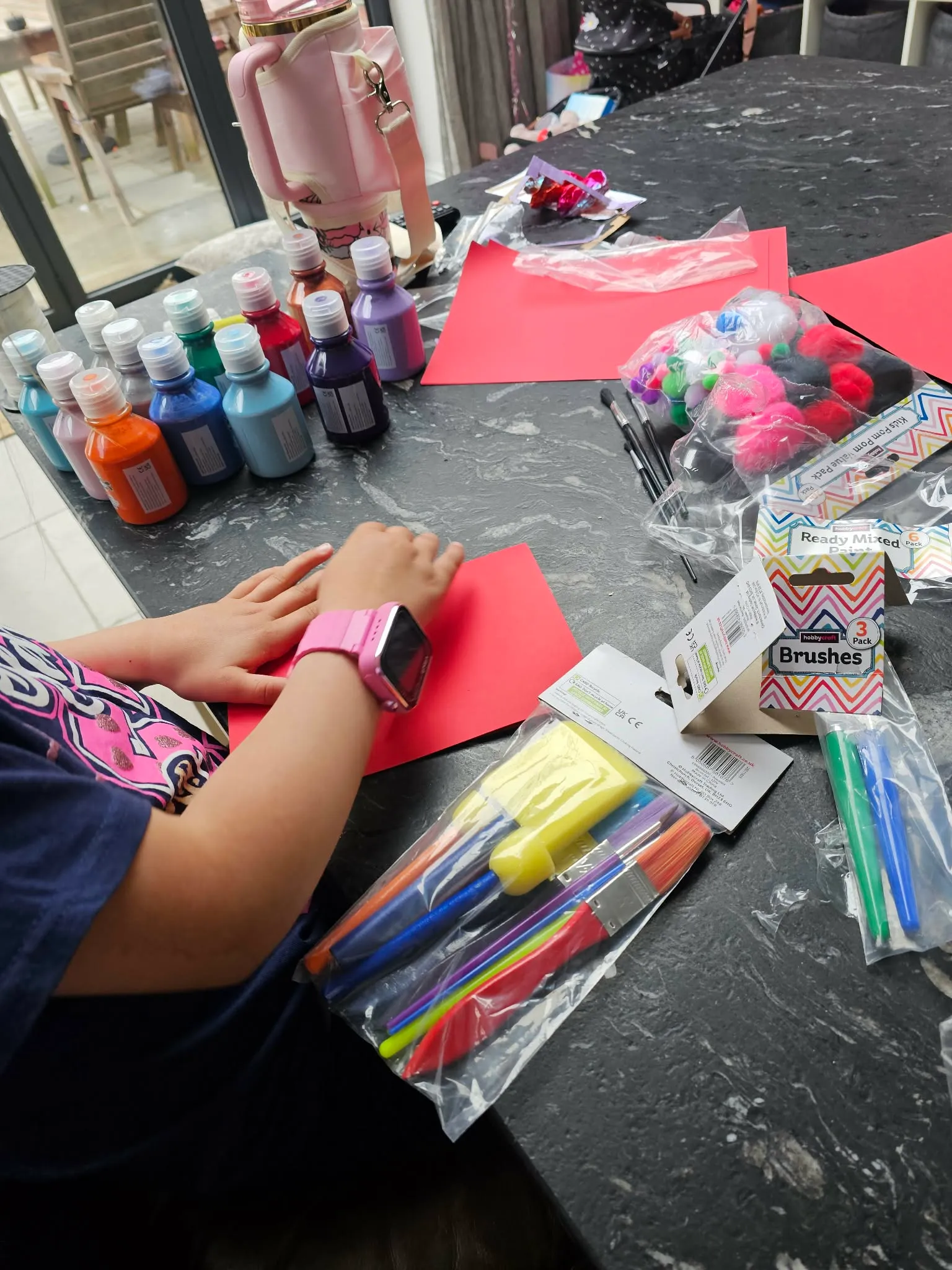A child painting and crafting at the kitchen table, paints lined up ready