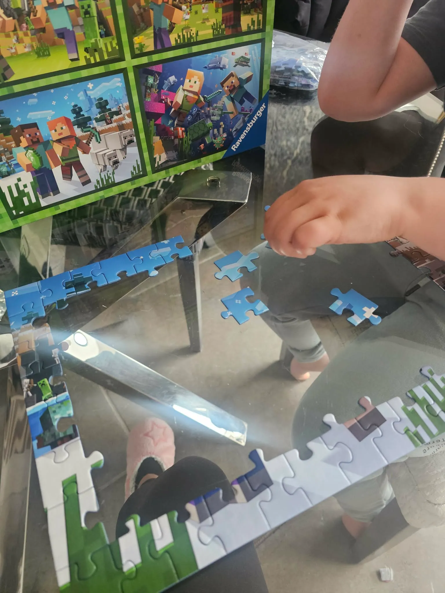 A child piecing together a jigsaw puzzle at a glass table